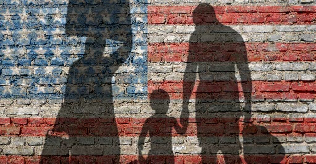 silhouette d'une famille portant des bagages avec le drapeau américain peint sur un mur de briques, pétition familiale